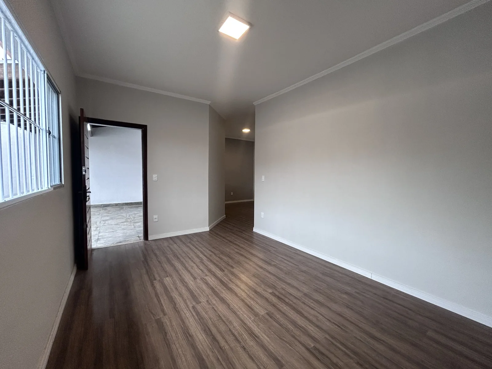 Sala de estar com piso amadeirado e iluminação no teto